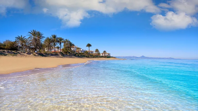 Playas españolas erosionadas con vista al mar y edificios cercanos, mostrando pérdida de arena.